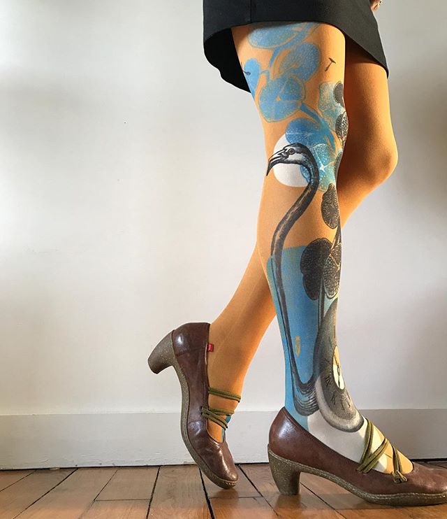 S'écarter des habitudes de la société 1 Collent excentrique. Collant vert avec un motif de flamant rose noir, un motif d'horloge noir, de fleurs bleues, rond blanc.
chaussure à talons marrons, jupe noire.