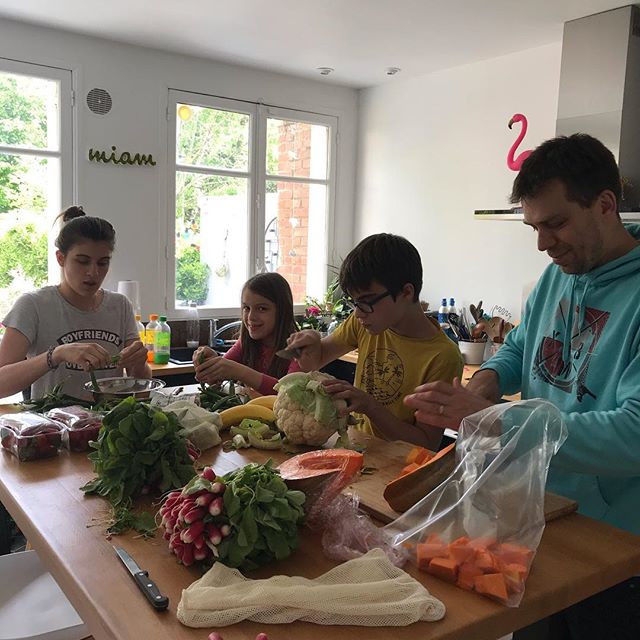 Famille de 3 enfants avec leur père qui font du batch cooking. Ils sont concentrés et souriant. 