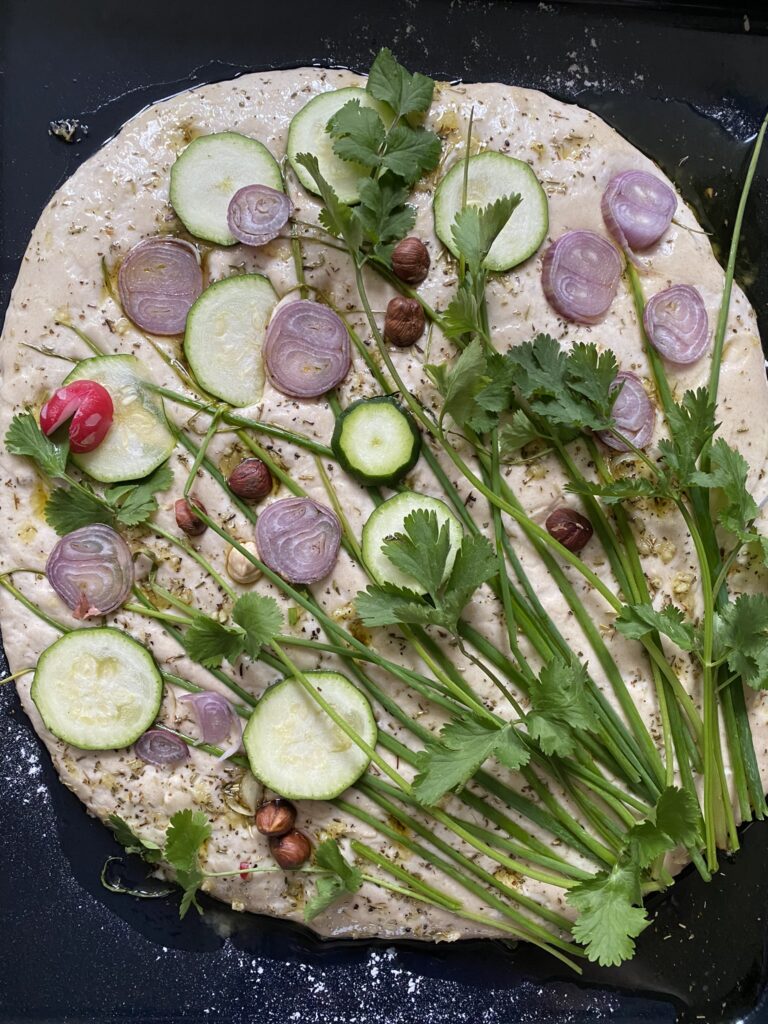 focaccia artistique décorée avec des herbes et des légumes qui forment un bouquet