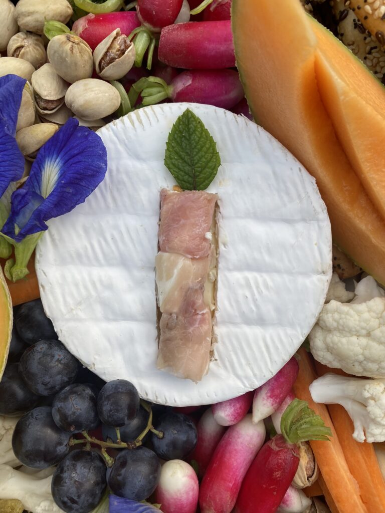 plateau apéro d'anniversaire avec une bougie posée sur un camembert